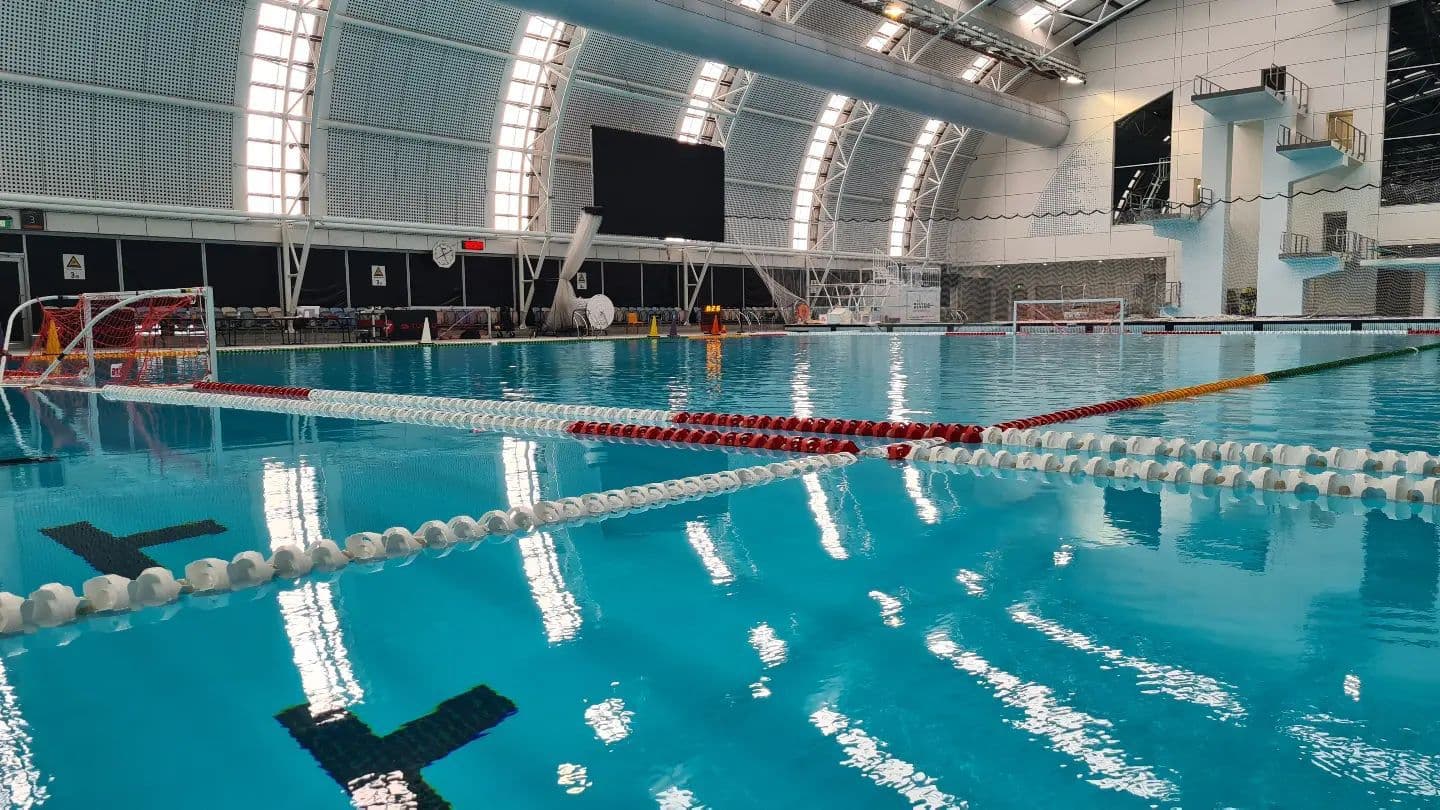 Indoor aquatic centre with lane ropes, water polo goals and diving towers