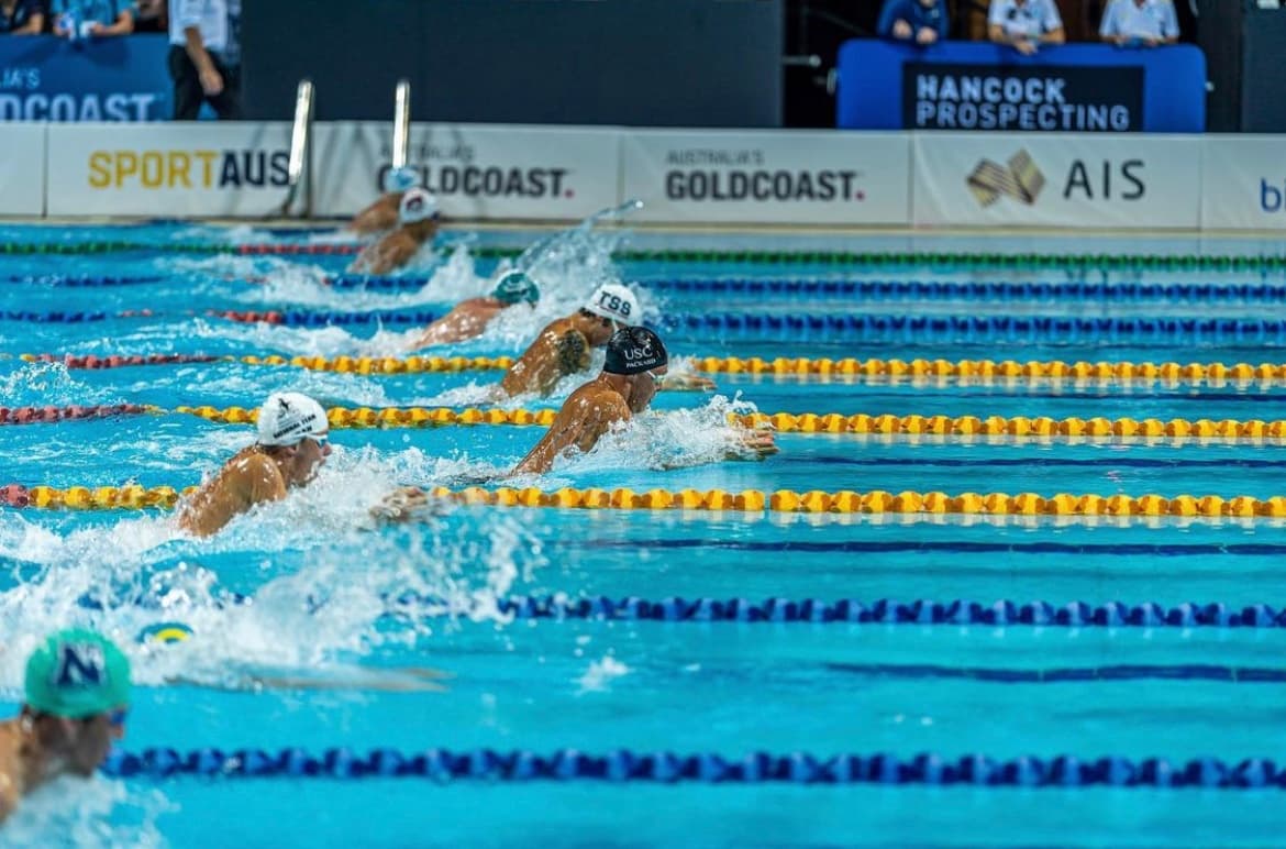Swimmers racing breaststroke down a lane pool at a competition