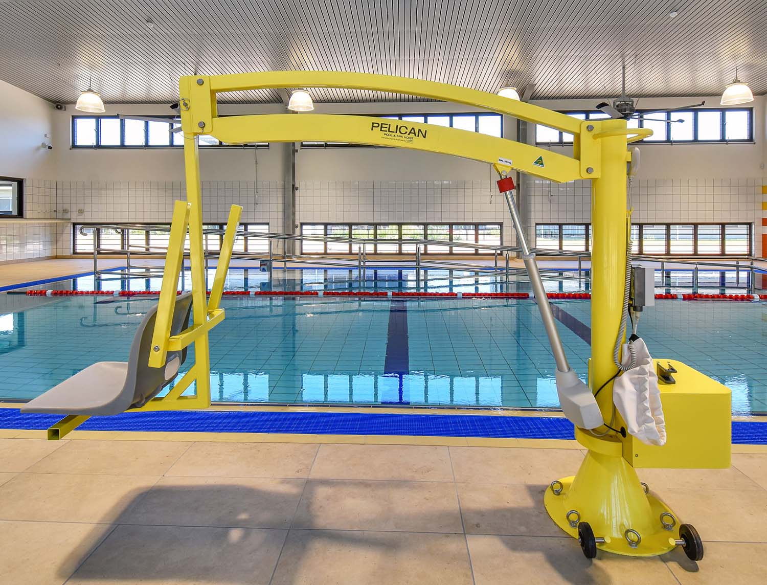 Yellow Pelican pool hoist poolside at an indoor accessibility pool